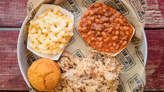 A platter with BBQ, baked beans, mac n cheese and cornbread