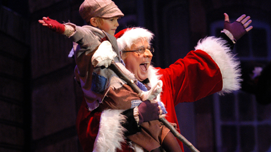 Scene from A Christmas Carol with a smiling, celebrating Scrooge and Tiny Tim