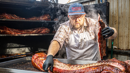 A pitmaster pulling barbecued pork