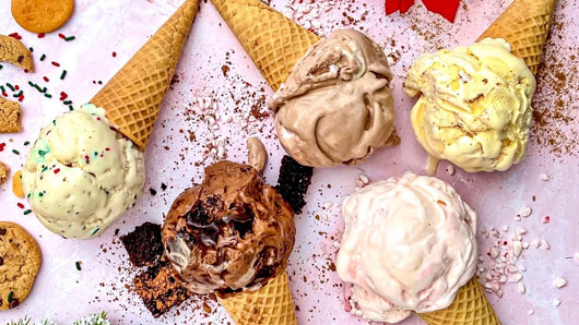 Photo of ice cream cones, with chocolate, vanilla and more flavors, on a pink table