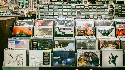 Vinyl record store filled with shelves of music; Queen and Prince have music front and center in photo