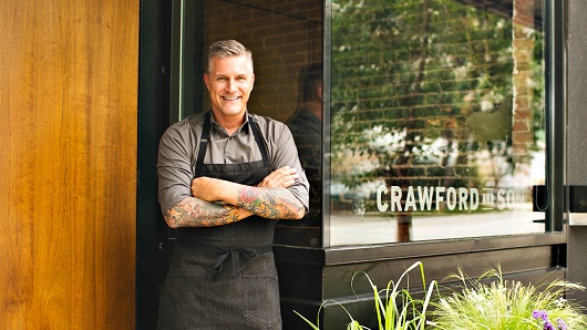 Chef Scott Crawford poses with a smile outside of his award-winning restaurant Crawford and Son