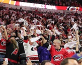 Carolina Hurricanes fans dressed in red, white and black stand, cheer and wave towels during a game at PNC Arena in Raleigh, N.C.