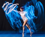 A female dancer in a white outfit twirls a baton on stage