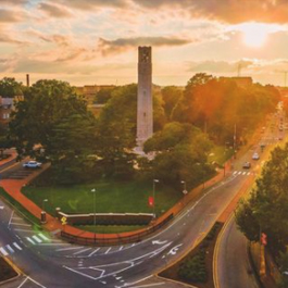 Aerial shot of the Memorial Belltower at North Carolina State University and Hillsborough St. during a sunset