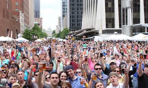 A crowd of beer drinkers raising their glasses to cheers
