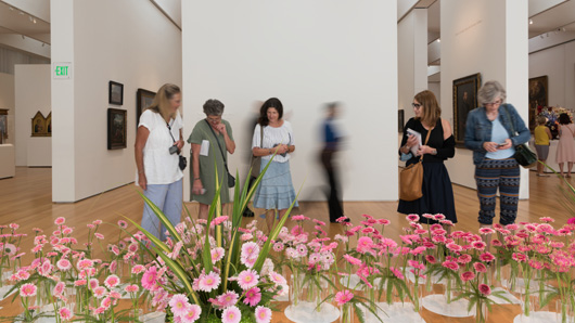 A group of people looking at artistic flower arrangements in a museum hall