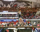 A woman walking on a balance beam in front of a large crowd
