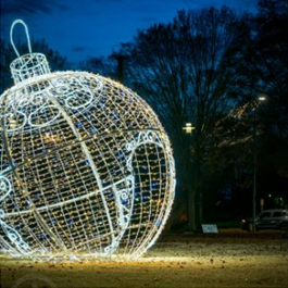 A giant ball ornament lit up, with a tunnel where people can stand under it and take photos