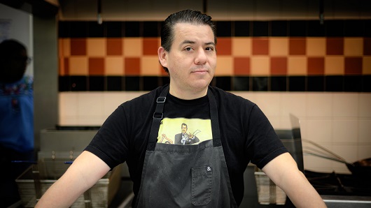 Portrait of chef Katsuji Tanabe wearing apron in kitchen of restaurant looking at camera