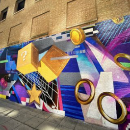 A colorful, huge outdoor mural depicting video game imagery, with coins, stars, yellow cubes with question marks and more