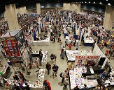 A top-down view of a convention floor full of booths and attendees taking part in activities