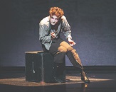 A male character from 'Dracula' sits on a box on stage, spotlight upon them, looking into the distance and pondering