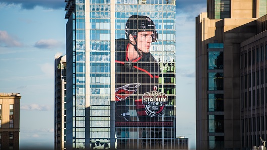 A larger-than-life graphic of Carolina Hurricanes player Andei Schveknikov, approximately 15 stories tall, on the side of the PNC Building in downtown Raleigh