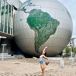 Woman posing in celebration in front of the giant globe at North Carolina Museum of Natural Sciences