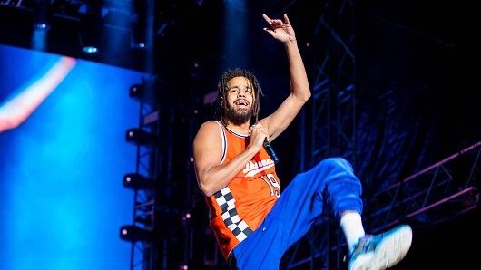 Photo of star J. Cole rapping from the stage at a live concert