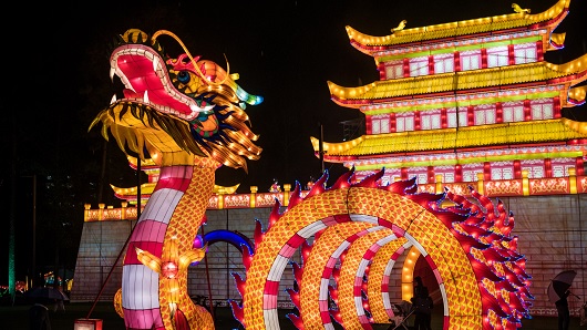 Traditional Chinese lanterns, a 20-foot-tall dragon and 30-foot-tall traditional Chinese building glow bright orange and red hues against a dark night sky