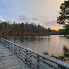 A wooden boardwalk stretching over a large, serene lake