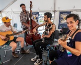 Four string musicians jam out under a tent at IBMA Bluegrass Live! powered by PNC