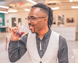 A portrait of a well-dressed Matthias Payton sipping on a drink while leading a workshop