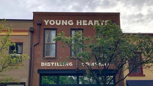 Exterior of a historic downtown building with Young Hearts Distilling Company painted in large letters