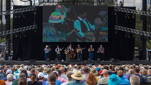 Big crowd at Raleigh's Red Hat Amphitheater during International Bluegrass Music Association's Bluegrass Live! festival with six musicians on stage in a line