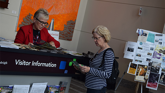 Julie speaking to a visitor at an information kiosk
