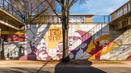 Photo looking straight on at a mural that celebrates Shaw University's 150th Anniversary, using red and yellow tones, featuring Ella Baker, a civil rights activist that graduated from Shaw in 1927
