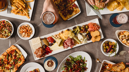 Overhead view of a table with beer, small plates and a big charcuterie board
