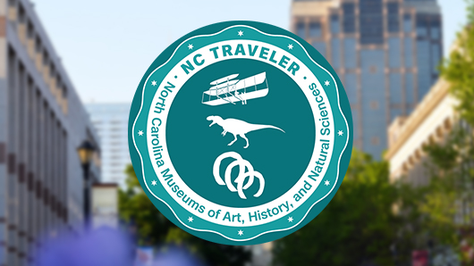 Round logo that reads "NC Traveler; North Carolina Museums of Art, History, and Natural Sciences" in aqua and white colors