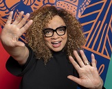 A portrait of Ruth E. Cater, wearing thick-framed glasses and a black top against a colorful orange and blue background. In March of 2023 Carter became the first Black woman to ever win multiple Oscar awards