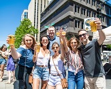 A group of friends raising a glass of beer on a downtown Raleigh street during Brewgaloo craft beer festival
