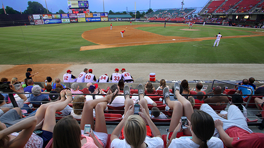A crowd watching a baseball game in the early evening