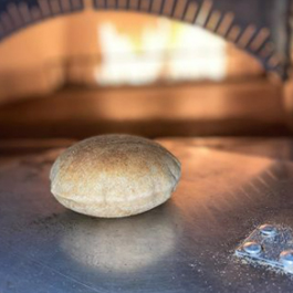 Freshly baked pita bread in front of a wood-fired oven