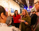 Woman leading a tour, speaking to a handful of guests circled around her inside a restaurant